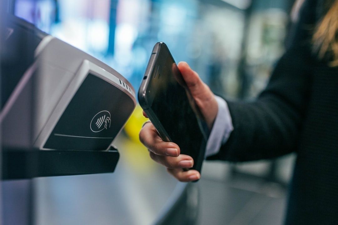 Person holds a smartphone beside a contactless payment terminal
